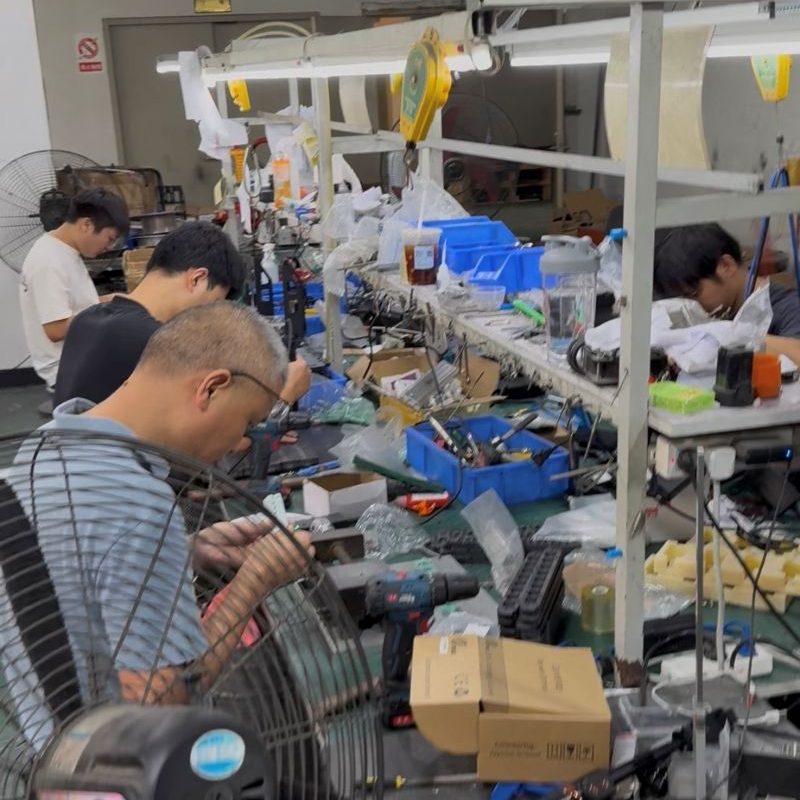 Factory workers assembling electronic test fixture components on production assembly line