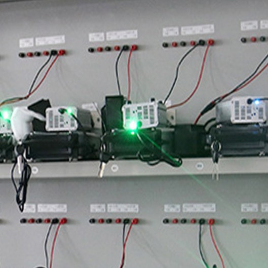 Detail view of battery aging cabinet test module with green indicator light, burn-in test fixture